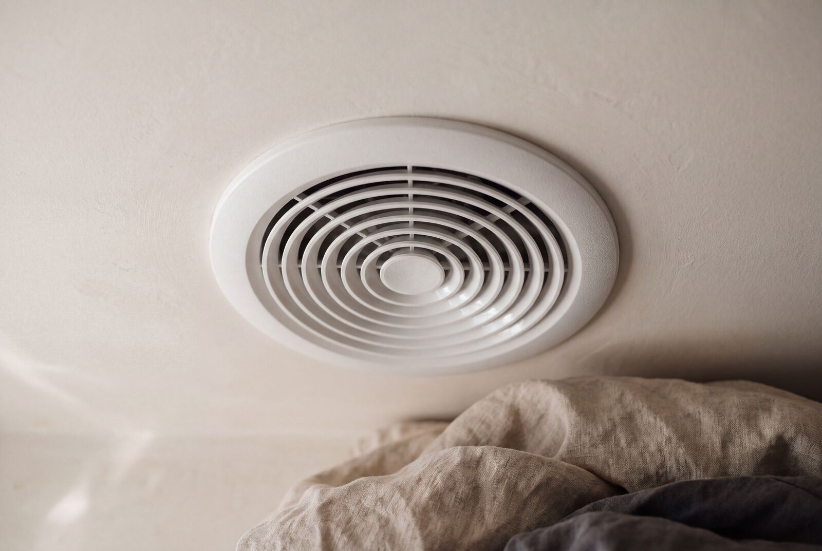 Product still: a round white ceiling vent on linen